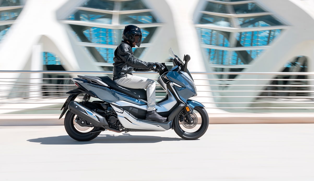 Honda Forza300 kjører foran en bygning